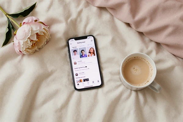 Flatlay of phone, peony, and oat latte representing the 2026 small penis dating guide